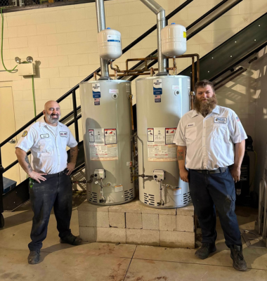 Photo of plumbers in front of hot water heaters